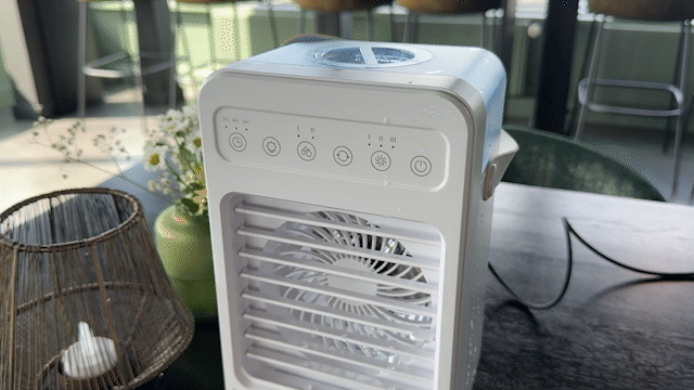 Person holding a compact white portable cooling device with control buttons on top.